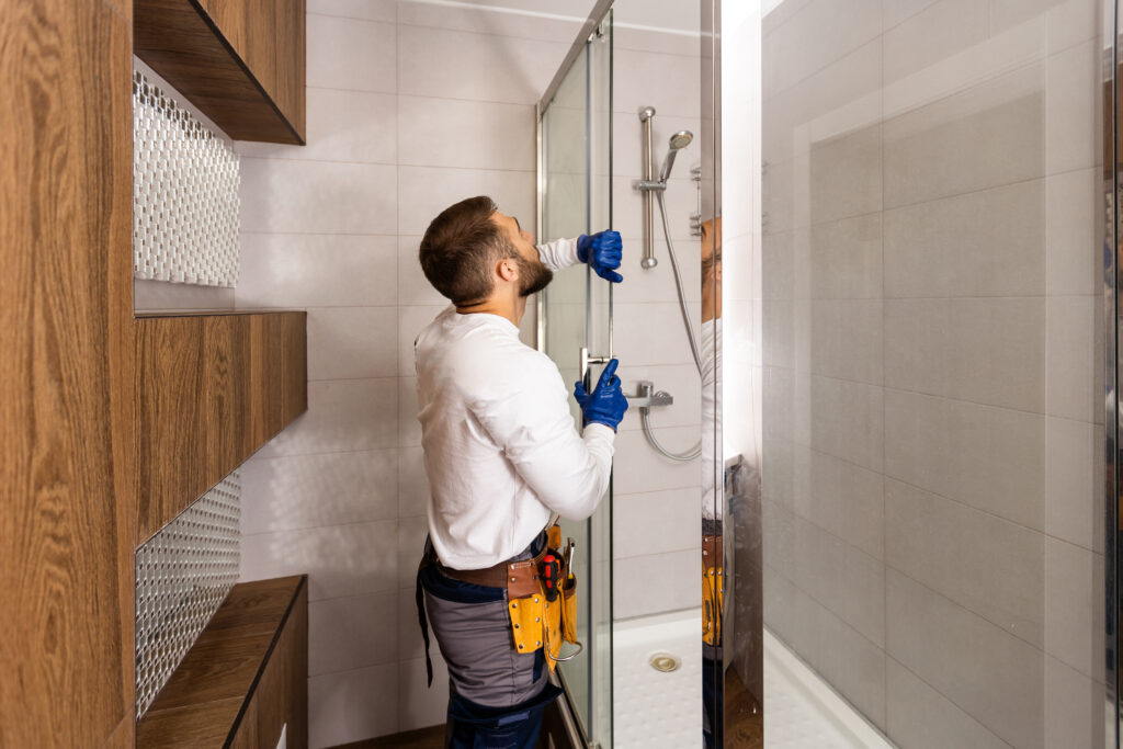 Der Installateur montiert die Glasduschwand im Badezimmer